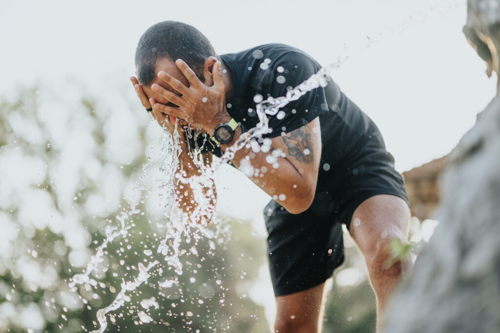 man splashing water from hose in face