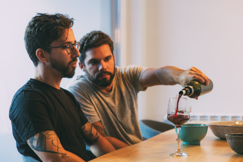 man pouring wine into another man's glass